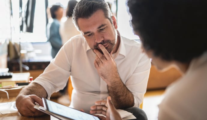 Homem olhando para outra pessoa que está usando um laptop